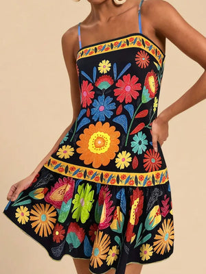 Black mini dress with vibrant floral print, yellow border trim, and spaghetti straps.