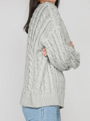 Grey cable knit openwork sweater with crew neck and long sleeves.