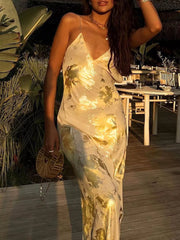 Cream maxi dress with abstract gold pattern, V-neck, and spaghetti straps.