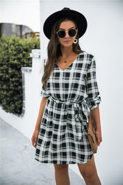 Black plaid shirtdress with V-neck, 3/4 sleeves, and belted waist.
