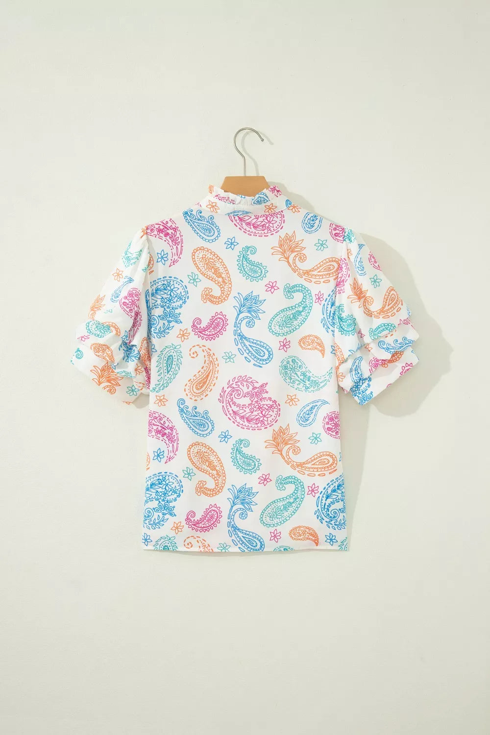 Maternity blouse with puff sleeves and vibrant paisley print in pink, blue, and orange on white.