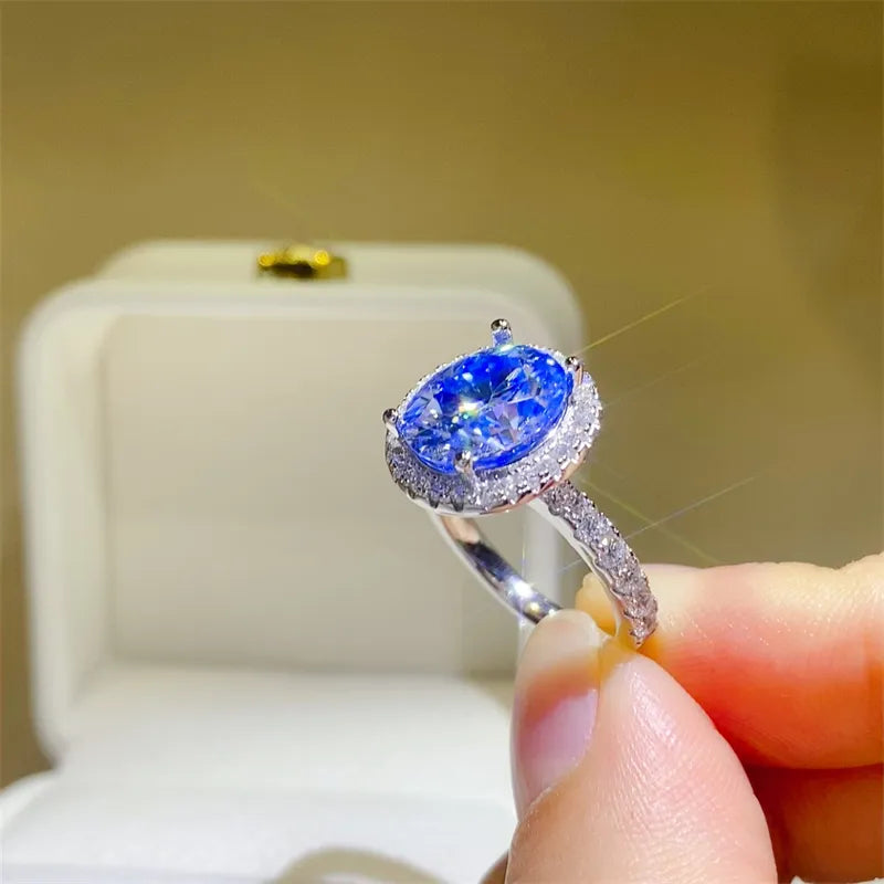 Silver halo ring with a bright blue oval moissanite center stone and diamond accents.