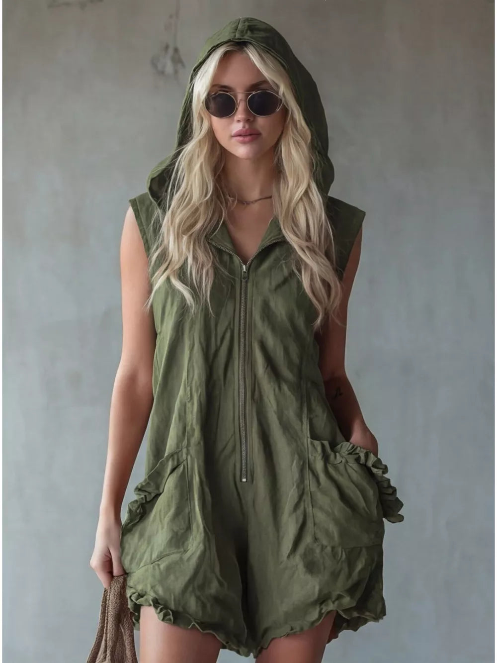 Army green hooded sleeveless romper with ruffled pockets and zipper front.