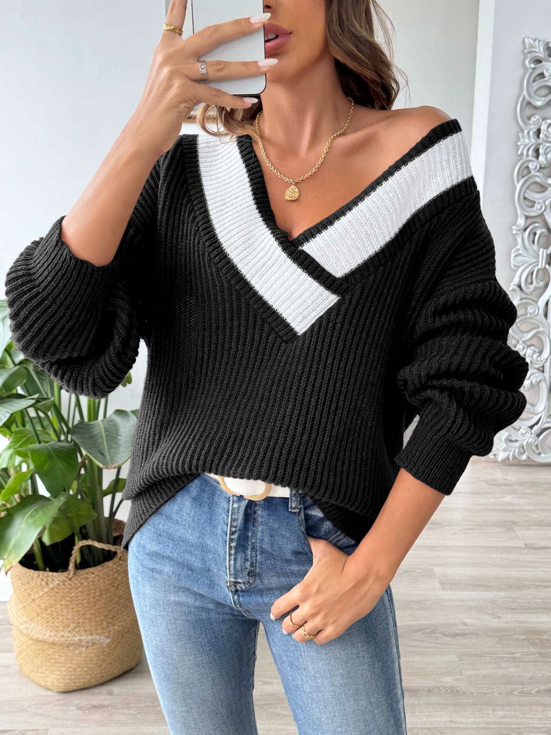Black knit sweater with off-shoulder V-neck and white contrast trim.