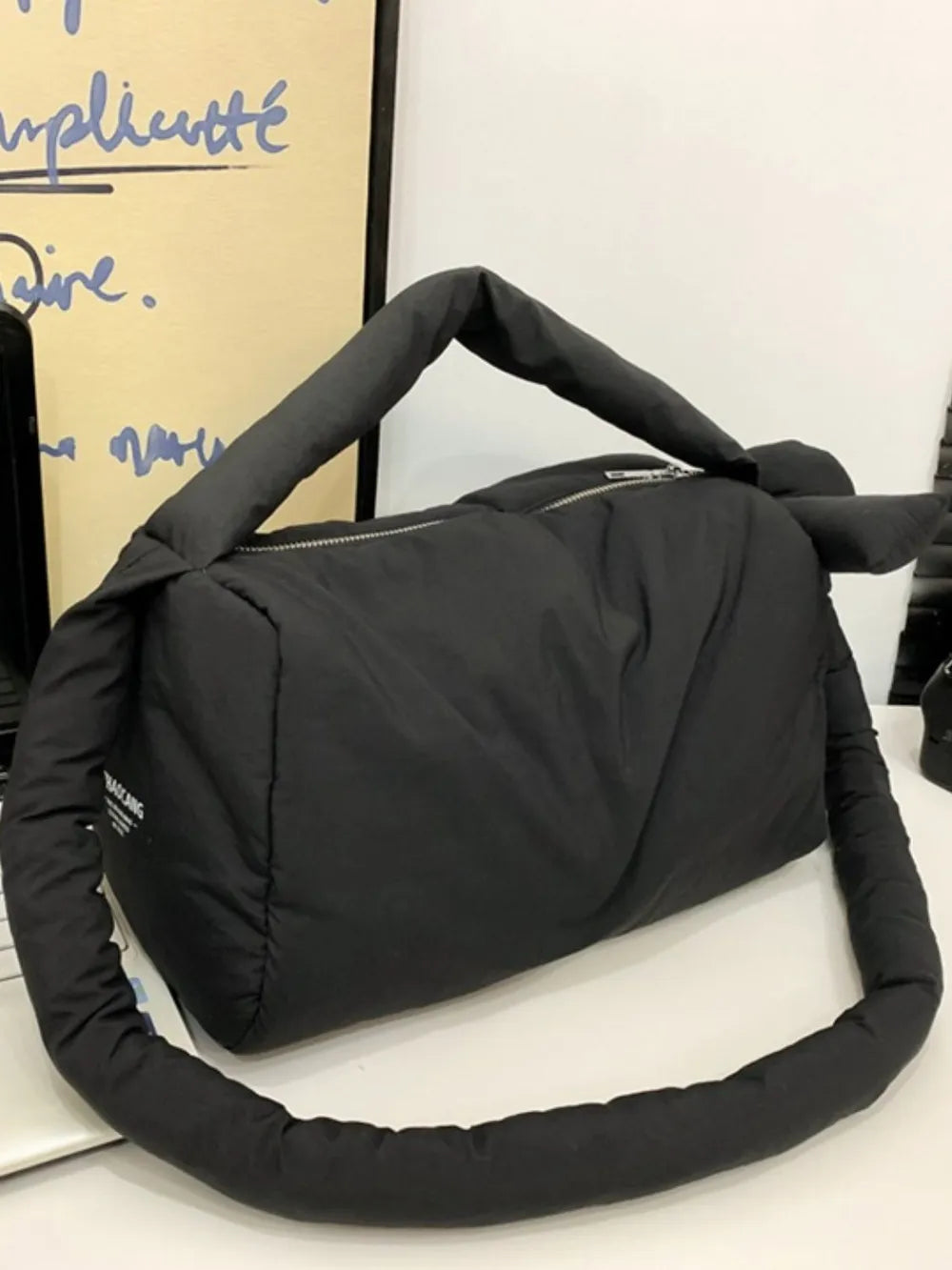 Black padded knot shoulder bag with a zip closure and puffy strap.