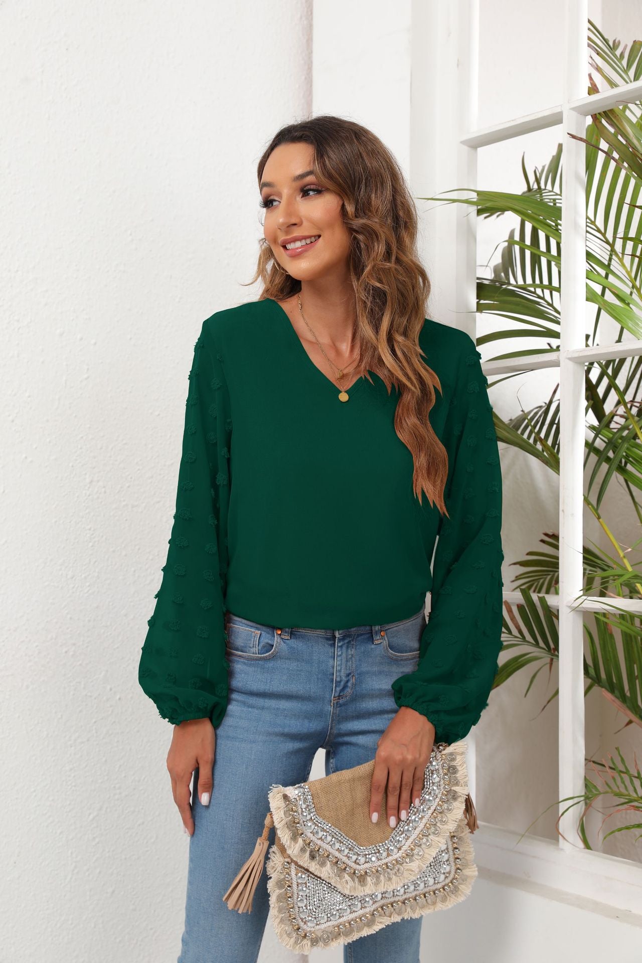 Forest green V-neck blouse with textured pom-pom sleeves and balloon cuffs.