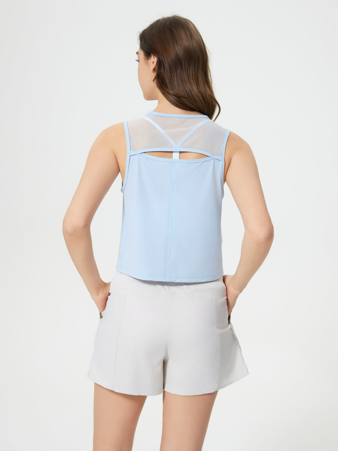 Light blue cropped active tank with mesh back detail and cutout.
