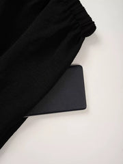 Black maternity pants with textured fabric and elastic waistband detail.