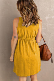 Yellow button-down mini dress with gathered waistline, sleeveless, and a brown shoulder bag.