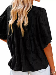 Black textured V-neck blouse with ruffled detail and short sleeves.