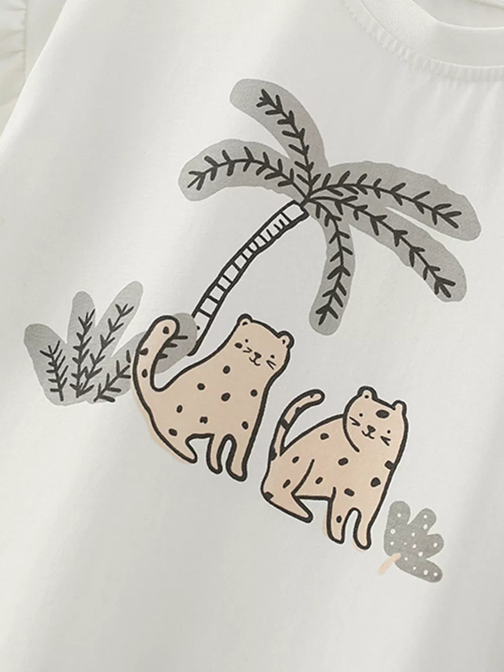 White cotton baby tee with playful wildcat and palm tree graphic print.