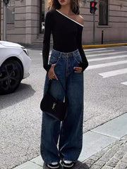 Black off-shoulder ribbed top with contrast trim, long sleeves, paired with wide-leg jeans.