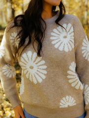 Tan knit sweater with textured white floral motifs, crew neck, long sleeves.