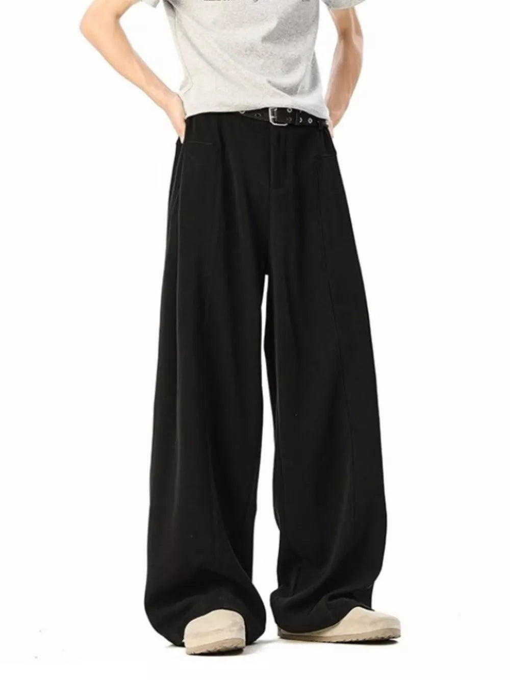 Men's black wide-leg track pants with a belt and light-colored shoes.