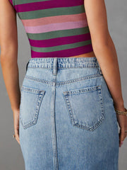 Light wash denim midi skirt with raw edge slit and buttoned waist.
