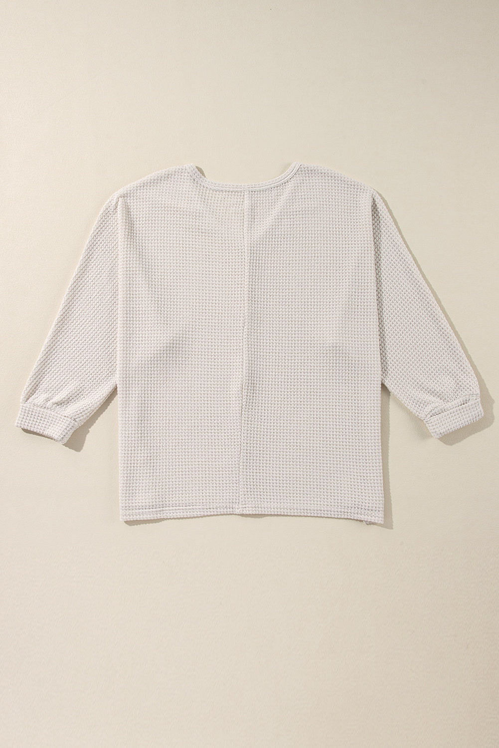 Beige waffle knit V-neck long sleeve top with cinched cuffs.