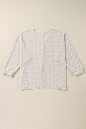 Beige waffle knit V-neck long sleeve top with cinched cuffs.