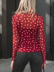 Sheer polka dot mock neck shirt in red with white dots, long sleeves, worn over a camisole.