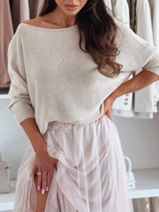 Cream off-shoulder batwing knit sweater with boatneck and ribbed cuffs.