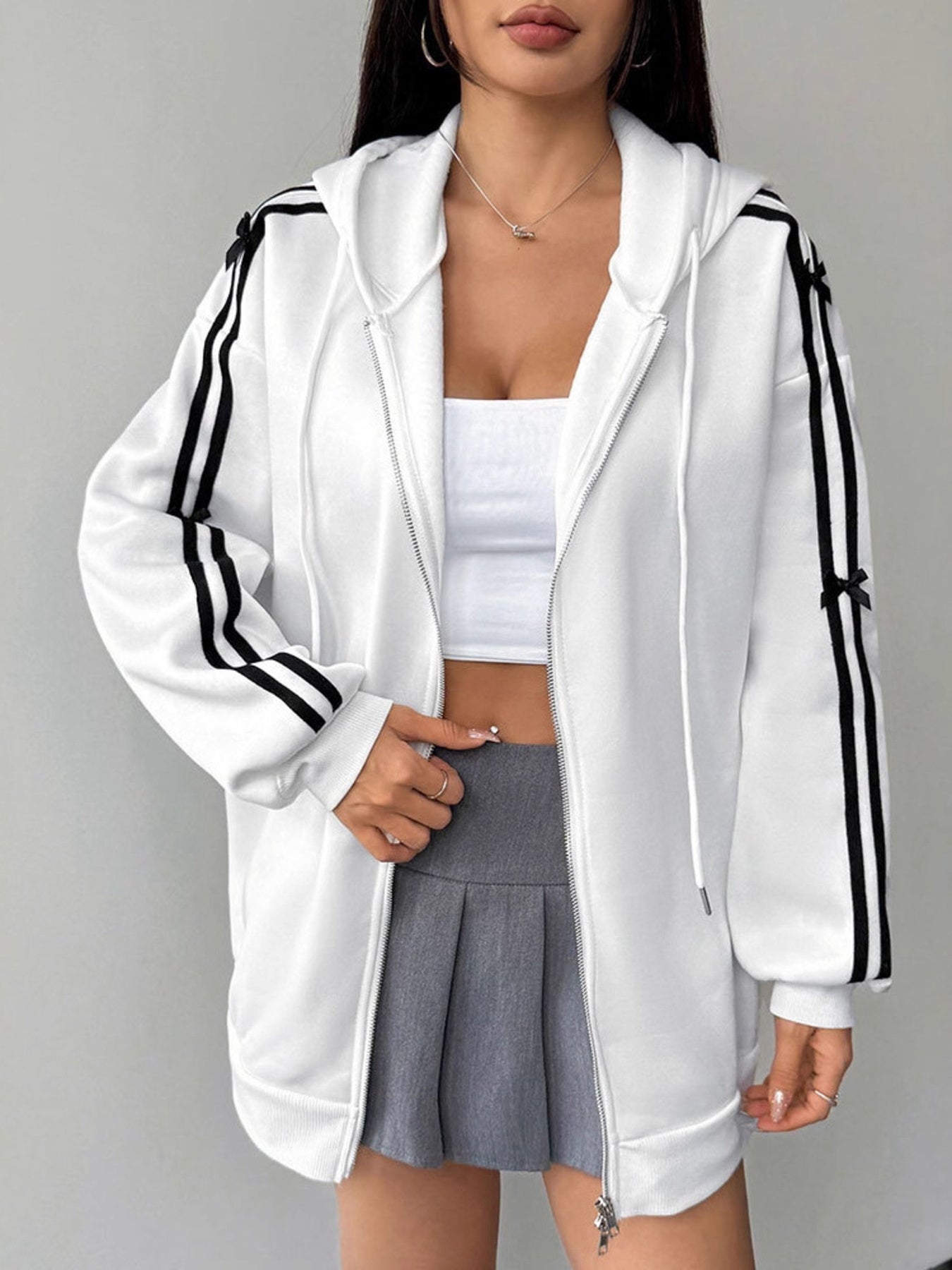 White zip-up hoodie with black stripes and bow details on sleeves.