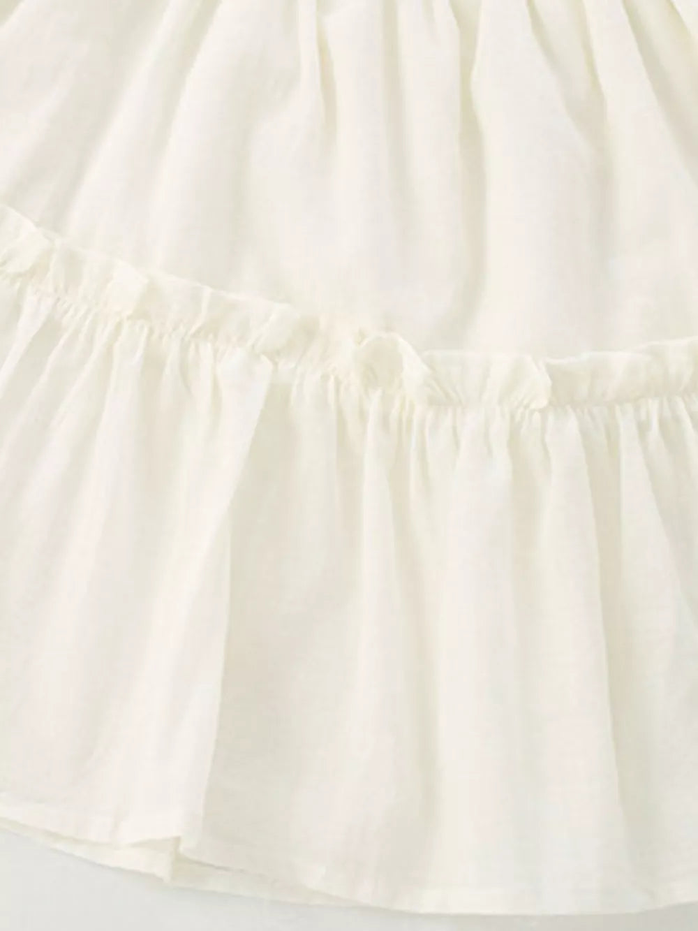 Cream tiered toddler dress with ruffled details and a cotton blend fabric.
