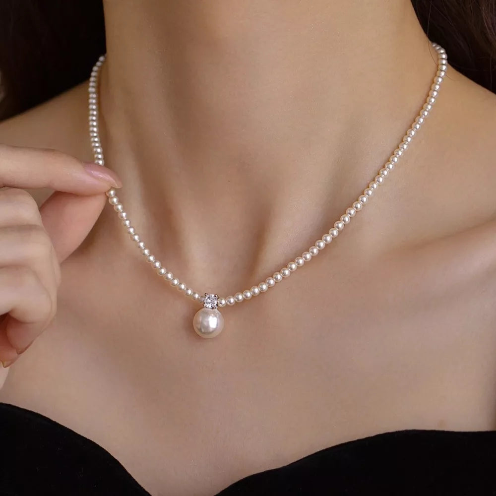 Luminous pearl pendant choker necklace with a single pearl drop and crystal accent.