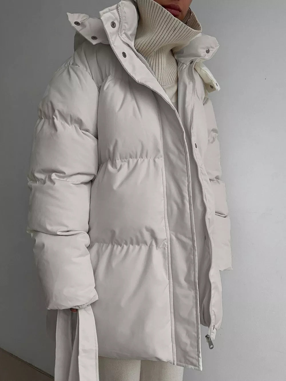 Thick puffer trench coat in ivory white with hood and belt detail.