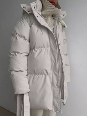 Thick puffer trench coat in ivory white with hood and belt detail.