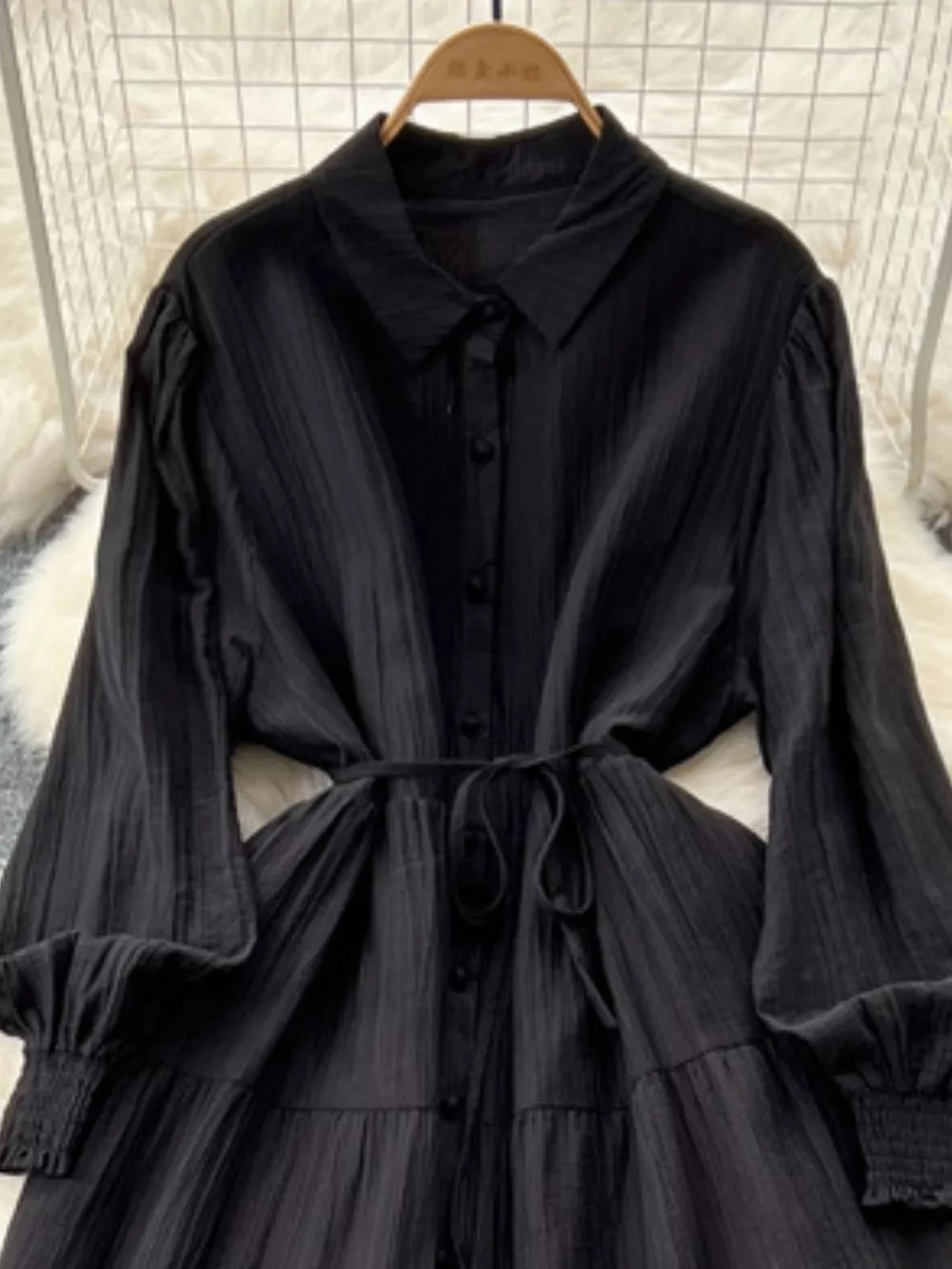 Black textured tiered long sleeve dress with button-down front and tie waist.