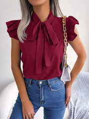 Burgundy pussy-bow blouse with ruffle sleeves and a tie neck, styled with jeans.