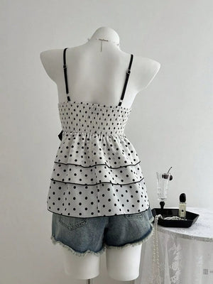 White polka dot camisole with black trim, smocked bodice, tiered ruffle hem, and adjustable straps.