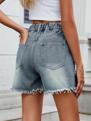 Medium wash denim shorts with frayed hem and studded side detail