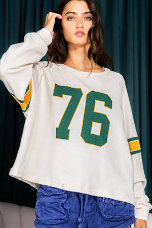 White raglan sleeve sweatshirt with green and yellow '76' graphic and sleeve stripes.