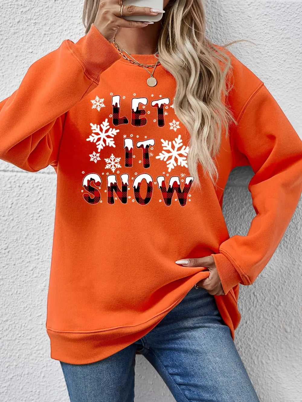 Orange crewneck sweatshirt with "Let It Snow" graphic and snowflakes.