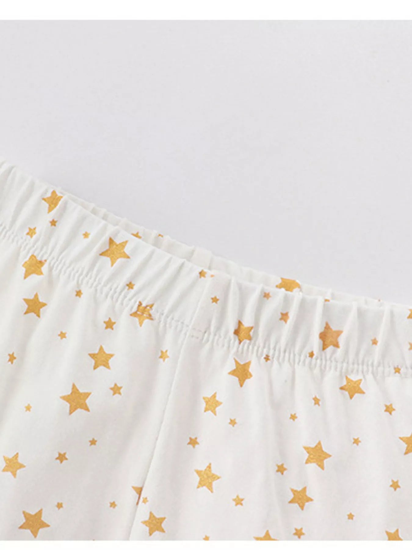 White cotton pajama pants with gold stars and elastic waistband