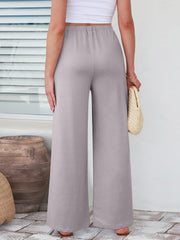Pleated palazzo trousers with pockets in light gray, featuring a wide leg and elastic waist.