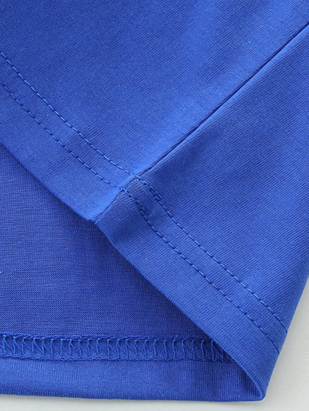 Blue cotton t-shirt detail showing seams and hem.