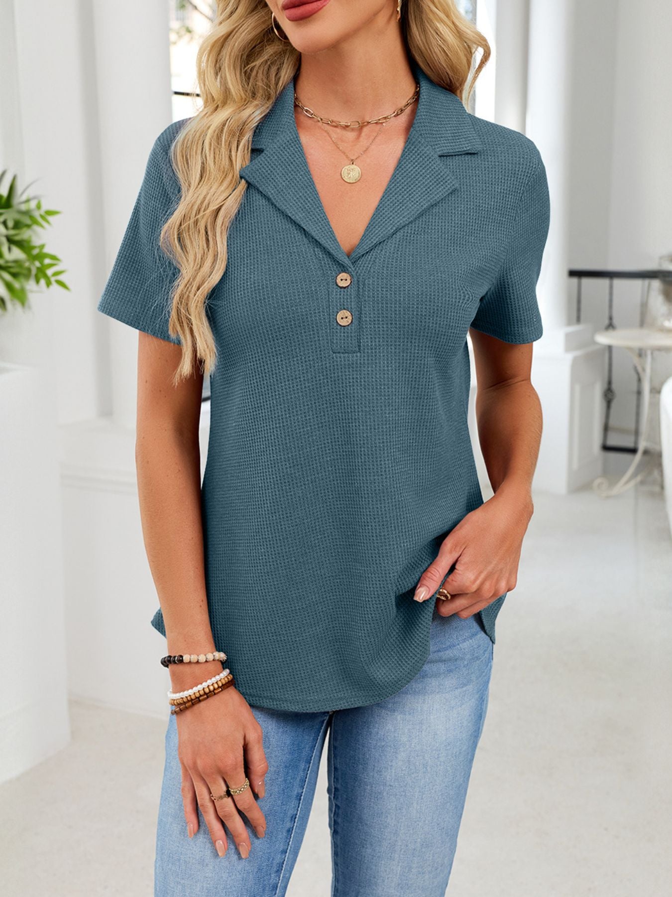 Peacock blue waffle knit button placket polo shirt with collared neckline and short sleeves.
