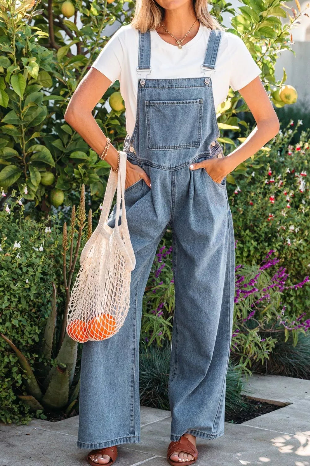 Denim wide-leg jumpsuit with pleats and buttoned sides, styled with a white tee.