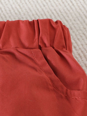 Toddler shorts with elastic waistband and pocket detail in rust orange cotton.