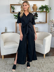 Black wrap jumpsuit with V-neck, short sleeves, tie waist, and high slit legs.