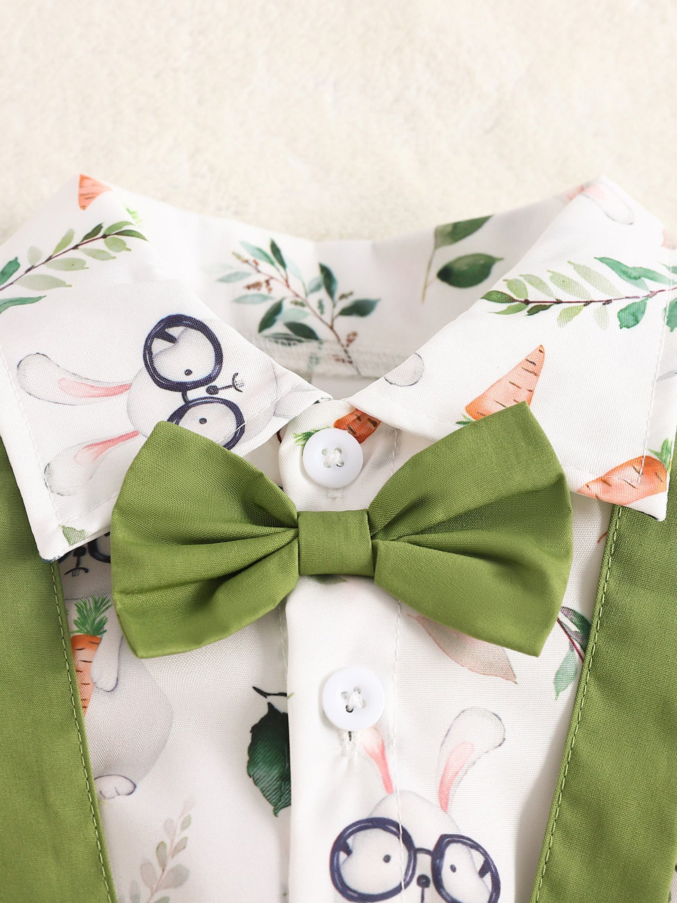 Baby cotton shirt with bunny and carrot print, green bow tie, and suspenders.