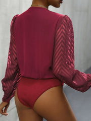 Deep Red bodysuit with chevron patterned sheer sleeves and a plunge neckline.