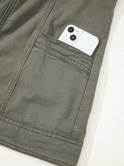 Ruffled denim vest in olive green cotton with a button closure and a phone in the pocket.