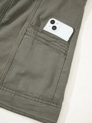 Ruffled denim vest in olive green cotton with a button closure and a phone in the pocket.