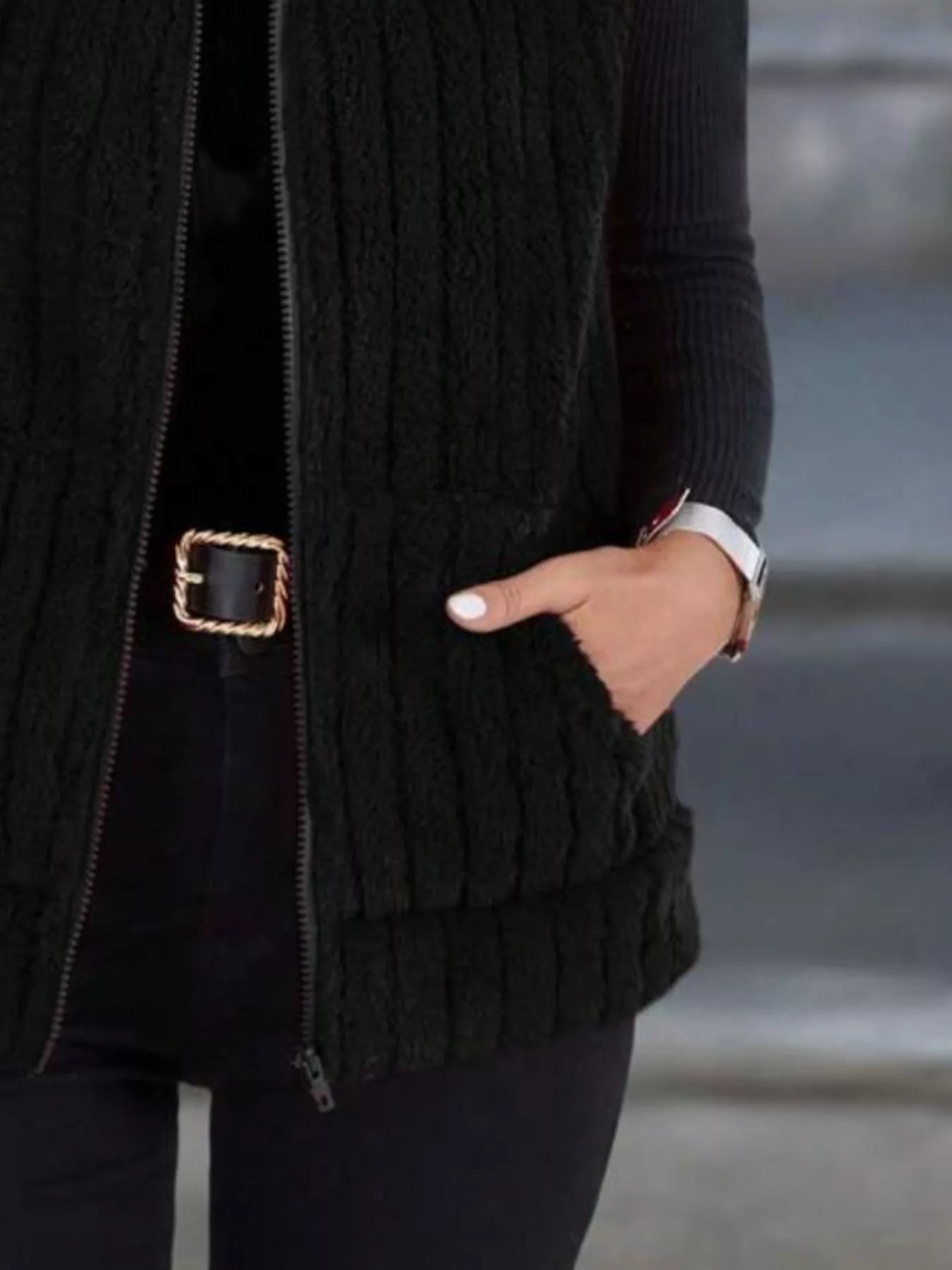 Black fleece zip-up vest with pockets and ribbed texture.