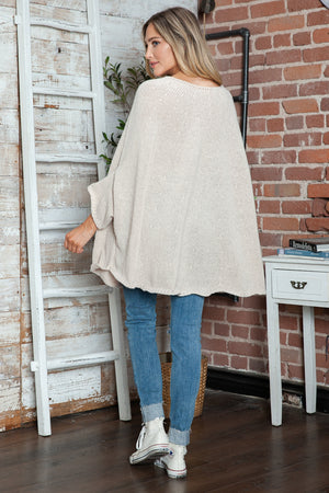 Cream knit cape sleeve sweater with wide batwing sleeves and a relaxed fit.