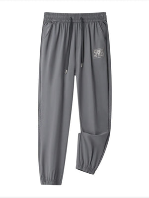 Grey casual drawstring joggers with logo detail and perforated side panels.