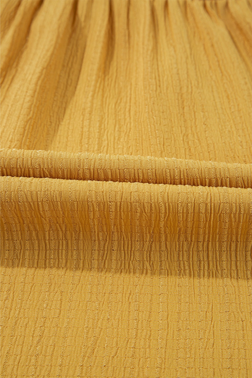 Mustard yellow textured blouse fabric with vertical ribbing detail.
