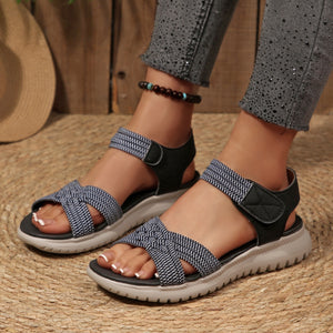 Woven strap open-toe flat sandals with adjustable velcro straps and a thick sole.